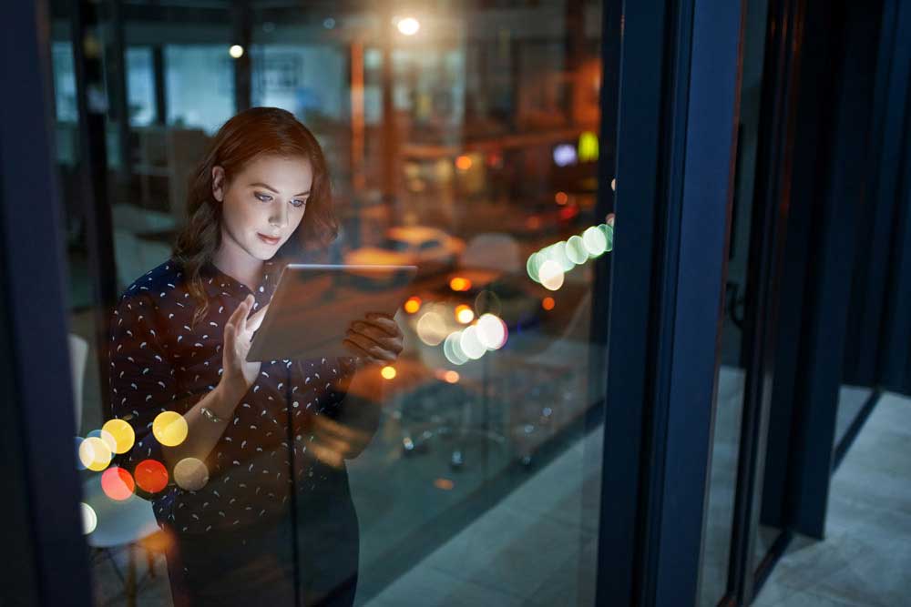 Woman with tablet behind glass.